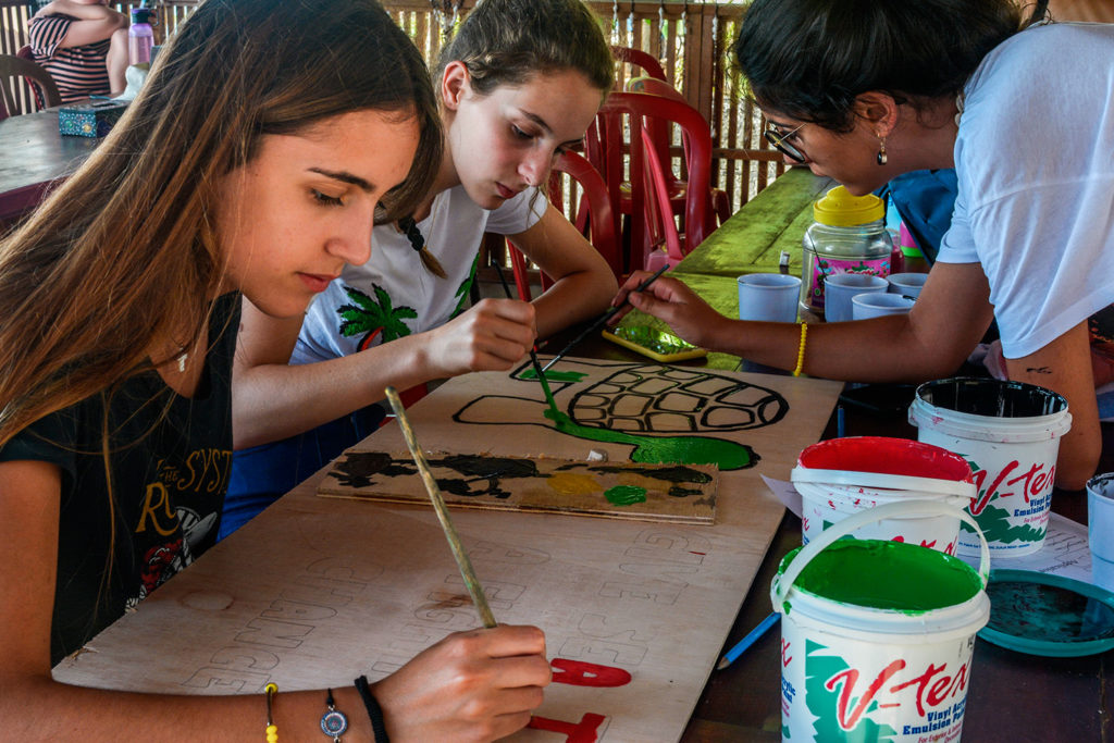 Volunteers painting a sea turtle conservation sign as part of a community project
