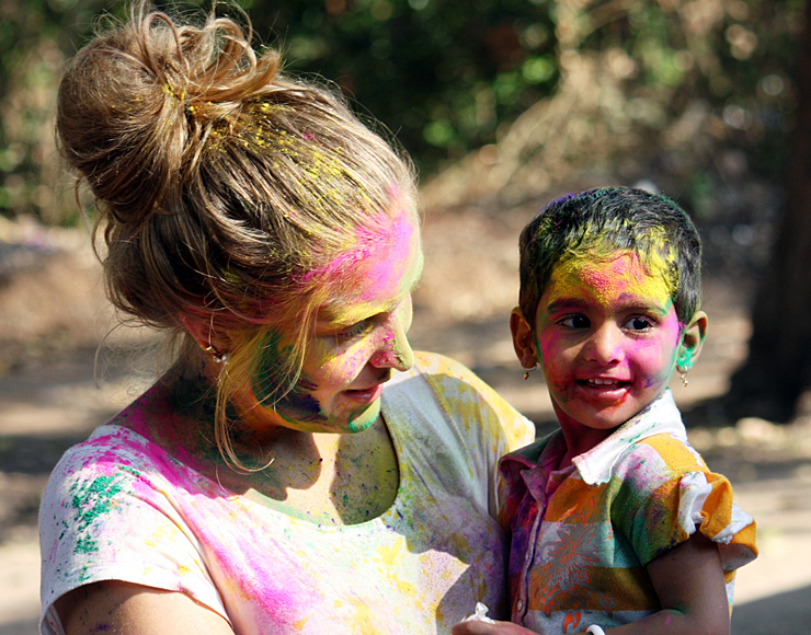 Volunteer and child celebrating with colourful powder during a community project in India