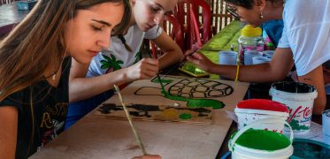 Volunteers painting a sea turtle conservation sign as part of a community project